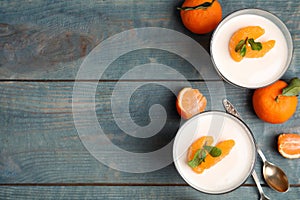 Delicious tangerine jelly and fresh fruits on light blue wooden table, flat lay. Space for text