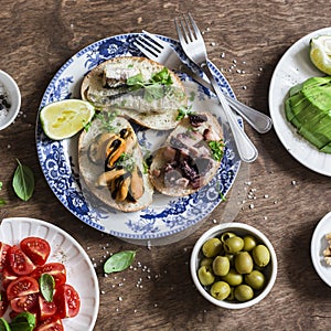 Delicious tapas - sandwiches with sardines, mussels, octopus, grape, tomato and avocado on wooden table