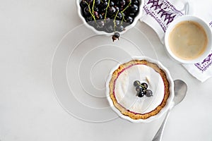 Delicious tart decorated with burned merengue and berries, served in white composition, with copy space. Top view.