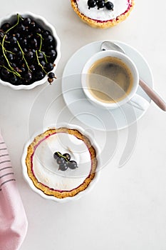 Delicious tart decorated with burned merengue and berries, served in white composition, with copy space. Top view.