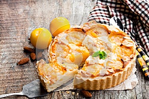 Delicious tart with yellow plum and almonds on wooden table photo