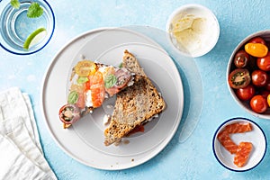 Delicious and tasty sandwich with salmon, basil, cherry tomatoes and caper. Close up selective focus. Traditional