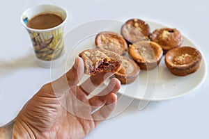 Delicious tasty homemade muffin bite and hold with the fingers of the hand. Coffee and served muffins on a plate to have a