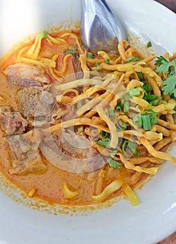 Delicious tasty Thai Northern Style Curried Noodle Soup with Beef in a bowl Khao Soi, Northern Thailand Food background close up