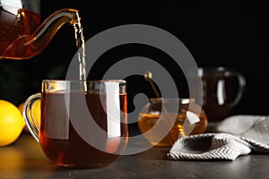Delicious tea pouring into cup and honey on table