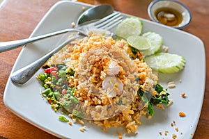 Delicious Thai food. Fried rice with egg, Kale served with minced red and green chilli in white plate on wooden table in cafe and