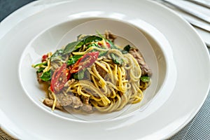 Delicious Thai fusion food, stirred fried spaghetti with thai green curry and meat. Beautiful Thai food in modern white dish on a