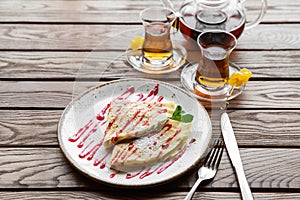 Delicious thin pancakes served with strawberry sauce on a wooden rustic table