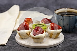 Delicious tiny tartlets tarts, open pastry pies on a dark background.