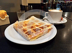 delicious toasted ham and cheese sandwich crumbs in triangles on white plate on a dark wooden table