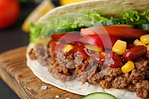 Delicious tortilla with meat and vegetables on wooden board, closeup