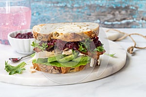 A delicious turkey and bacon club sandwich with avocado and cranberry sauce.