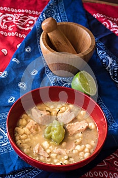 Delicious typical Central American dish called pozole served in a red bowl full of stew made of meat, corn, chili and other
