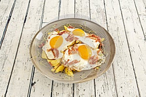 Delicious typical Spanish dish to share with broken eggs, ham slices and fried potatoes
