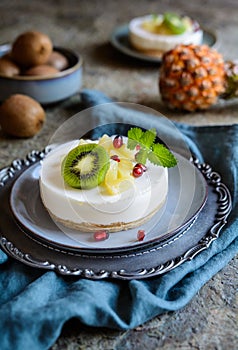 Unbaked mini cheesecakes topped with pineapple, kiwi and pomegranate
