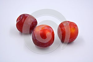 Delicious useful fruits, red, cherry ripe plums located on a white background.