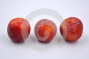 Delicious useful fruits, red, cherry ripe plums located on a white background.