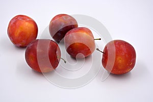 Delicious useful fruits, red, cherry ripe plums located on a white background.