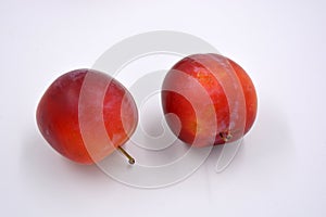 Delicious useful fruits, red, cherry ripe plums located on a white background.