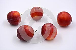 Delicious useful fruits, red, cherry ripe plums located on a white background.