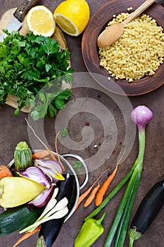 Delicious useful porridge cous cous in a clay plate and raw fresh vegetables in a basket