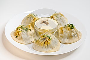 Delicious uzbek dumplings on a white plate. Manti with lamb meat. POV