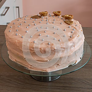 Delicious vanilla cake topped with a creamy frosting and decorated with silver pearls and golden flowers