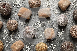 Delicious vegan candy balls and desiccated coconut on grey table, flat lay