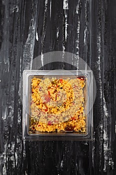 Delicious vegetarian couscous with tomatoes, carrots, zucchini, yellow bell pepper in plastic box