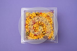 Delicious vegetarian couscous with tomatoes, carrots, zucchini, yellow bell pepper in plastic box