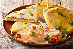 Delicious vegetarian fried Pupusas served with coleslaw close-up on a plate. horizontal