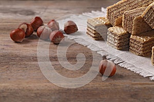 Delicious wafers with hazelnuts on brown wooden background