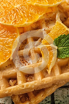 Delicious waffles with orange slices, closeup