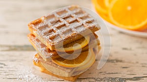 Delicious waffles with orange slices on a light background