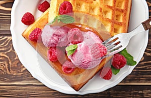 Delicious waffles with raspberries and ice cream on plate