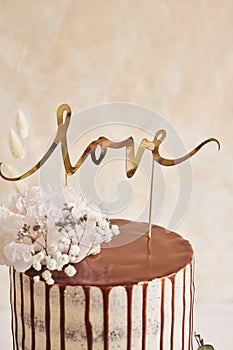Delicious Wedding cake with chocolate drip and love topper on a white table with white background