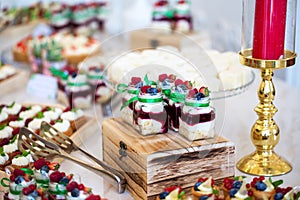 Delicious wedding reception candy bar dessert table full with cakes and sweets and a candles