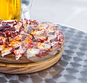 Delicious Wooden plate of galician style cooked octopus and Glass of cold beer . Pulpo a la gallega