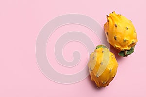 Delicious yellow pitahaya fruits on light pink background, flat lay. Space for text