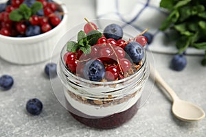 Delicious yogurt parfait with fresh berries and mint on light grey table, closeup