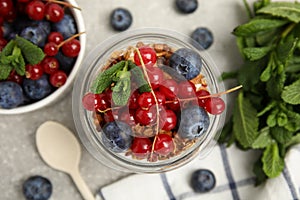 Delicious yogurt parfait with fresh berries and mint on light grey table, flat lay