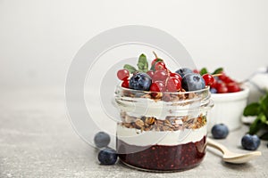 Delicious yogurt parfait with fresh berries and mint on light grey table, space for text