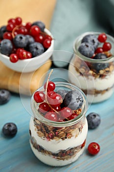 Delicious yogurt parfait with fresh berries on turquoise wooden table, closeup