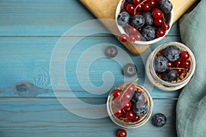 Delicious yogurt parfait with fresh berries on turquoise wooden table, flat lay. Space for text