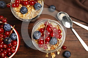 Delicious yogurt parfait with fresh berries on wooden table, flat lay