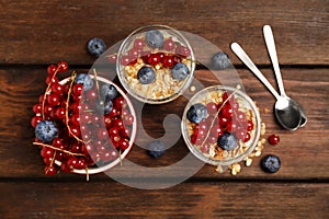 Delicious yogurt parfait with fresh berries on wooden table, flat lay