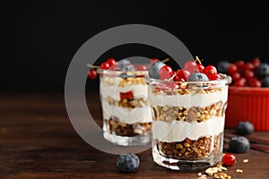 Delicious yogurt parfait with fresh berries on wooden table, space for text