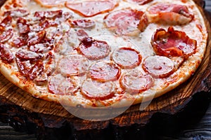 Delicious yummy fresh pizza with bacon, salami, ham and pepperon