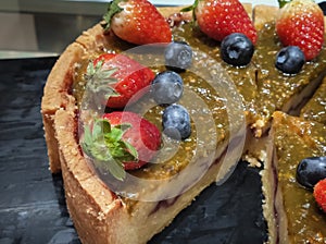 Deliciously sweet passion fruit pie with fresh strawberry and blueberry on topping.