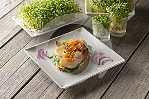 Delicius salmon toast with purpple onion and fresh sproutes. photo